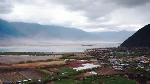 Fields and village beside a broad river in a Tibetan valley Stock Footage 345880891