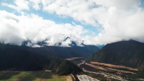 Fields and water basins below snowy forested Tibetan mountains Vidéo 345881747