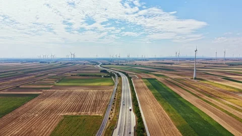 Fields and wind turbines span across the landscape with long roads cutting Stock Footage 342721452