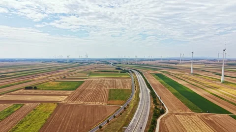 Fields and wind turbines stretch across a flat landscape near a highway on a Stock Footage 342784907