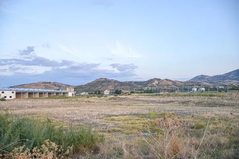 Fields in sunset factory and wind turbine in background Stock Photos