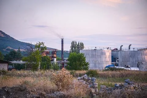 Fields in sunset factory and wind turbine in background Stock Photos