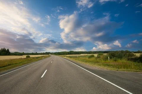Fields, trees and road with blue sky and clouds. Sun day. Stock Photos