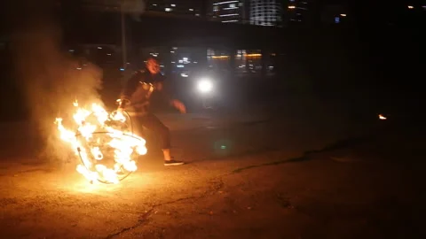 A fiery circus actor spins a burning hemisphere.Fiery performance. A man spins a Stock Footage 168928599