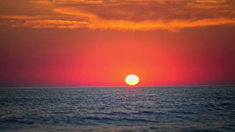 Fiery evening sky and glowing sun over calm ocean water, stunning nature footage 库存影片 335490289