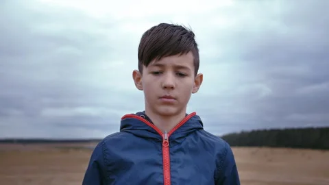 Fiery Gaze: Angry Boy Staring at the Camera Outdoors in Cloudy Weather Video stock 240149407