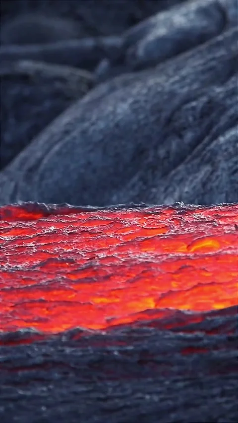 Fiery Lava Flow Glowing Among Dark Volcanic Rock Video stock 323298535