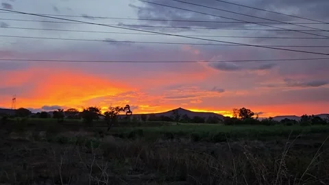 A fiery orange and purple sunset blankets the evening sky over a tranquil Indian Vídeo Stock 340905980