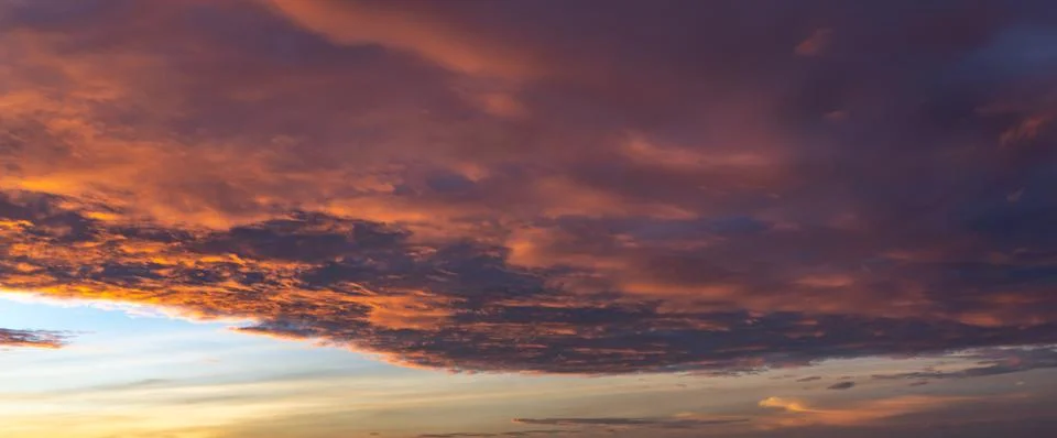 Fiery orange cloud on dramatic sky at sunset Stock Photos