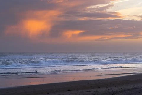 Fiery orange clouds above ocean waves. Stock Photos
