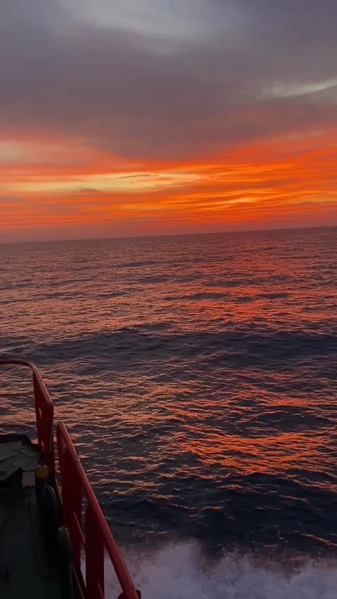 Fiery Orange Sunset Sky Over the Ocean Horizon from a Boat Deck Stock Footage 319019456