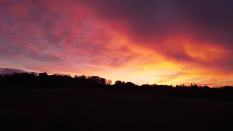 Fiery, peaceful sunset, slow downward movement before trees, drone shot 스톡 동영상 140221561