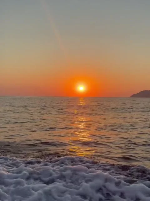 Fiery Red Sun Setting Over Calm Sea with Sailboat Silhouette Stock Footage 339882003