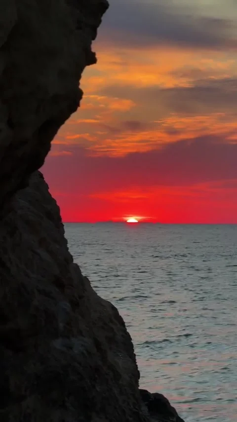 Fiery Red Sunset over Ocean Framed by Rock Cliff Silhouette Stock Footage 339774622