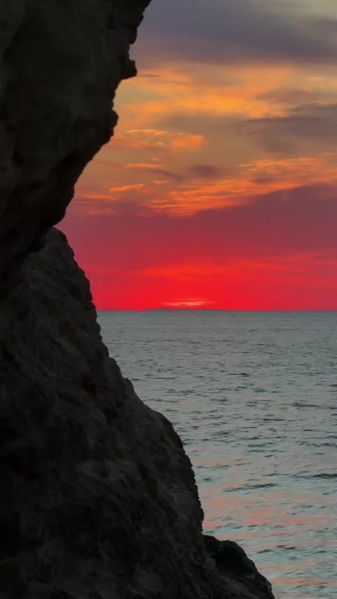 Fiery Red Sunset over Ocean Framed by Rock Cliff Silhouette Stock Footage 339774635
