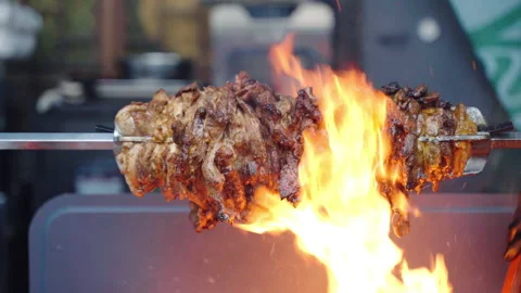 Fiery roasting of fat pork meat pieces on rotating spit, burning fire grilling Stock-Footage 164603434