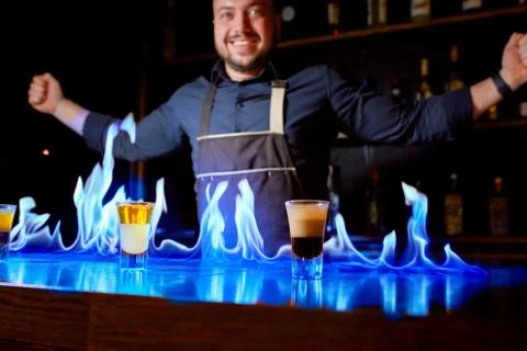 Fiery show at the bar. The bartender makes hot alcoholic cocktail and ignites Stock Photos