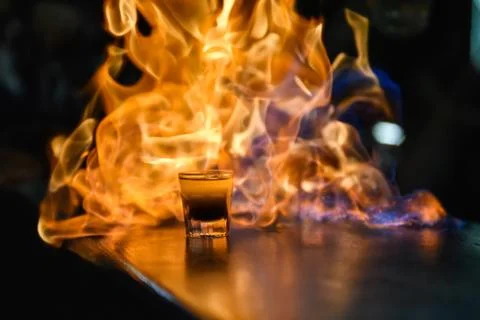 Fiery show at the bar. The bartender makes hot alcoholic cocktail and ignites Stock Photos