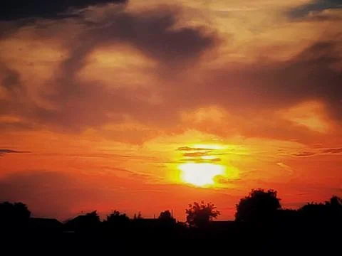 Fiery Sky with Distant Sun in Darkness 写真素材