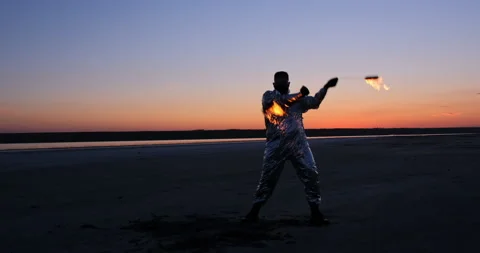 A fiery spinner in a silver suit spins torches 動画素材 152343572