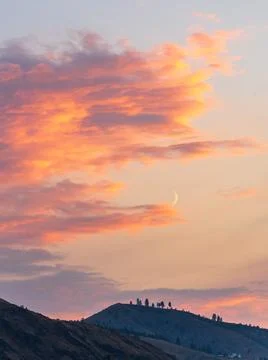 Fiery sunset clouds enveloping the new crescent moon over Lake Chelan Fotos Stock