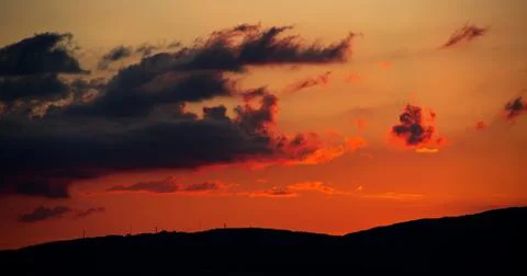 A fiery sunset in the clouds goes behind the mountains. Photos