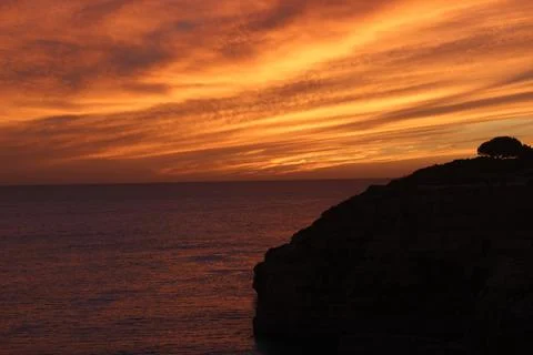 Fiery Sunset Clouds over Sea and Cliff in the Algarve, Portugal Fotos de archivo