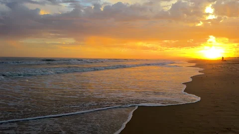 Fiery sunset colors reflect on the wet sand and rolling waves. Stock Footage 291346958