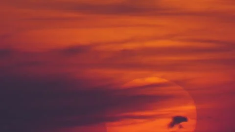 A fiery sunset descends over the horizon, casting warm hues across a cloudy.. Stock Footage 290087177