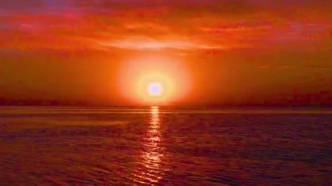 Fiery sunset glowing over calm ocean waters creating vibrant horizon Stock-Footage 341969337