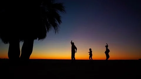 Fiery sunset by the ocean. Figures of a dancing family. Two adults and two Stock Footage 82851813
