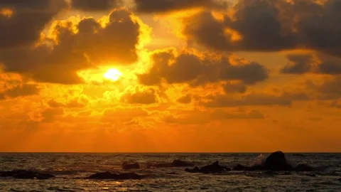 Fiery Sunset Over Ocean with Silhouetted Rocks and Dramatic Clouds Stock Footage 301066830