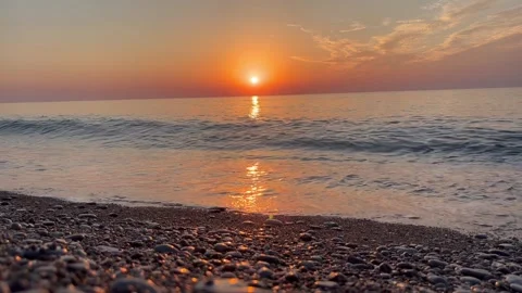 Fiery sunset over the sea on a pebble black beach, red sun, beautiful waves Stock Footage 290165426