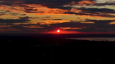 Fiery Sunset: Red Sun Setting Behind the Horizon with Dramatic Cloudscape Stock Footage 287576112