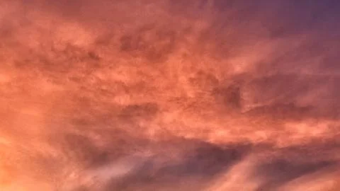 Fiery sunset sky with wispy clouds and warm hues Stock Photos