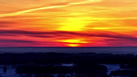 Fiery winter sunset timelapse with layered orange and red clouds over a dark Stock Footage 333326596