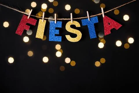 Fiesta word made of shiny paper and pins on black background and bokeh lights Stock Photos