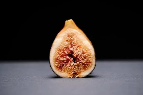 Fig split in half on a grey surface on a black background Stock Photos