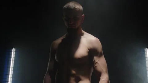 A fighter with a bare muscular torso is standing and looking at the camera. Vídeo Stock 274481775