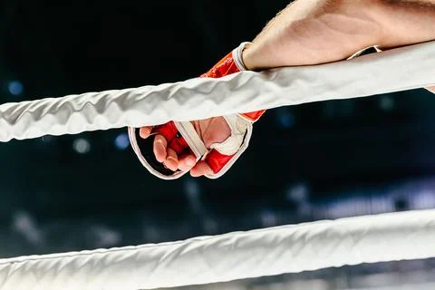 Fighter hand in red glove lies on white rope ring Stock Photos