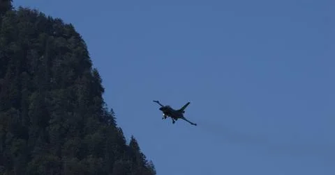 Fighter Jet Approaching Landing Against Blue Sky And Forest Backdrop Stock Photos