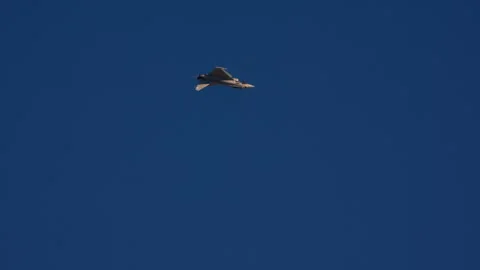 Fighter jet banking at high altitude against deep blue sky Stock Footage 346383643