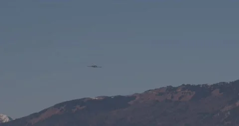 A fighter jet flies low in front of the mighty mountains Stock Footage 228711908