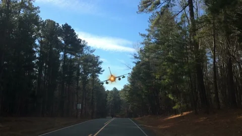 Fighter jet plane aircraft flies over a car driving down country road Stock Footage 209549129