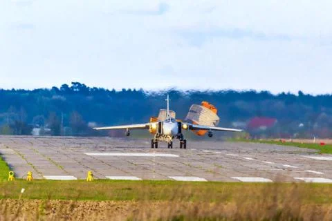 A fighter jet slows down while landing by throwing parachutes on its back. Stock Photos