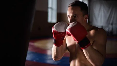 Fighter Practicing Some Kicks With Punching Bag - A Man On dark Background Stock Photos