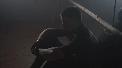 Fighter resting during workout in front of mirror. Young man sits alone in gym Stock Footage 95746418