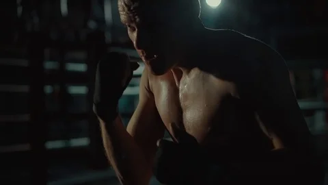 Fighter is working on training in boxing school, view of his figure in darkness Stock Footage 98744236