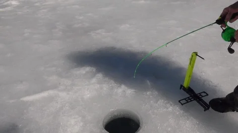 Fighting and Landing a Fish Through the Ice Stock Footage 123537397