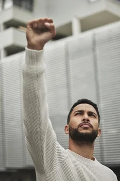 Fighting for what matters. Low angle shot of a handsome young man raising his Stock Photos